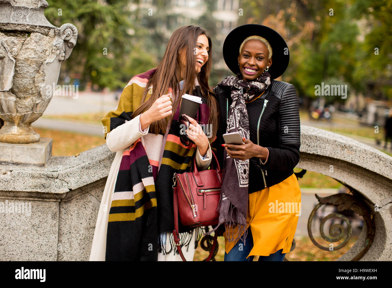 Giovane americano africano e caucasico donne tenendo selfie outdoor Foto Stock