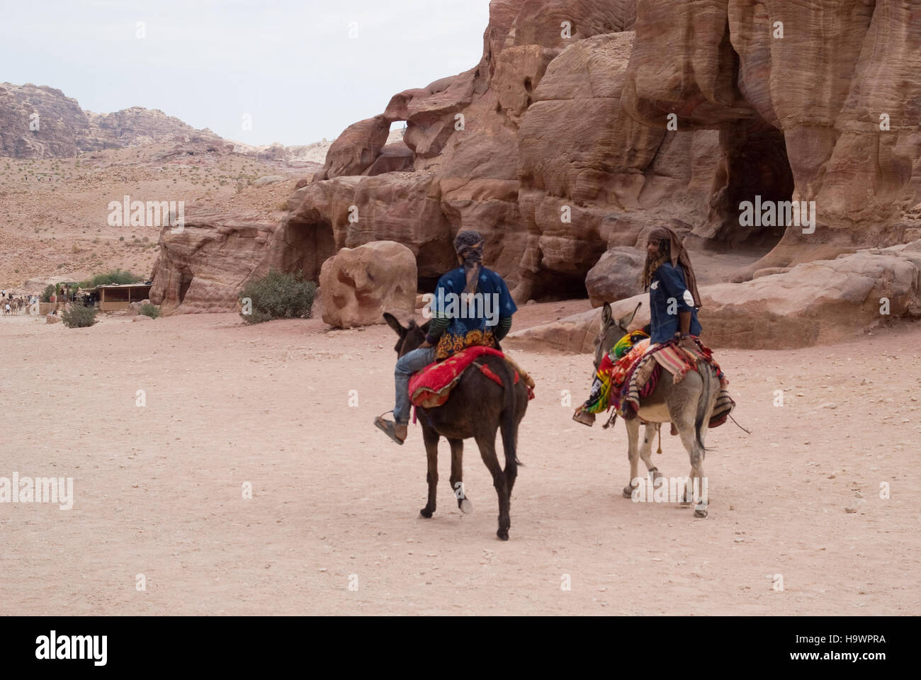 Beduin uomini a cavallo degli asini nelle antiche Nabatean città di Petra, Giordania Foto Stock