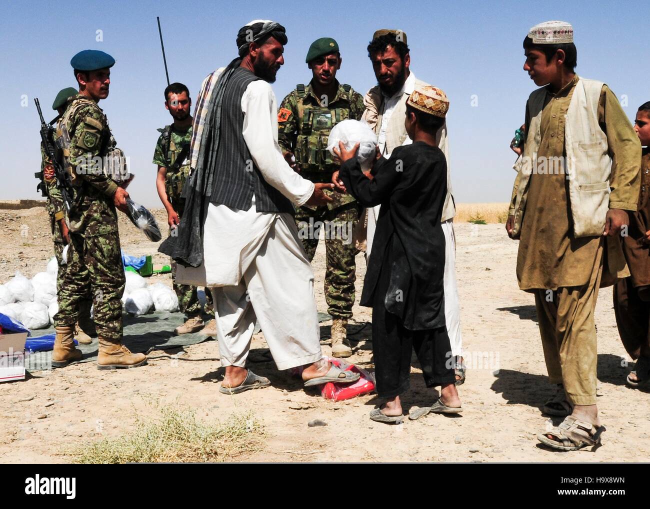 Afghan anziani la mano di un bambino a pallavolo durante un esercito nazionale afghano evento umanitario Giugno 11, 2014 in Miragul Kalay village, provincia di Kandahar, Afghanistan. Foto Stock