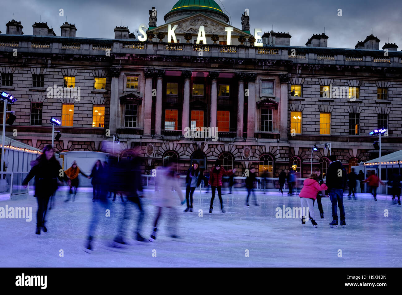 I pattinatori divertirsi sul ghiaccio a Somerset House Londra al tramonto. Foto Stock