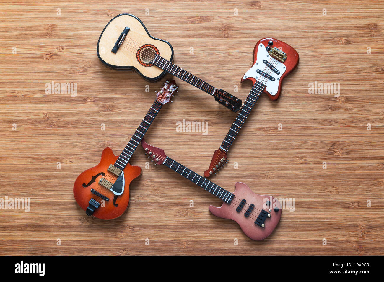 Set di quattro chitarre su uno sfondo di legno. Foto Stock