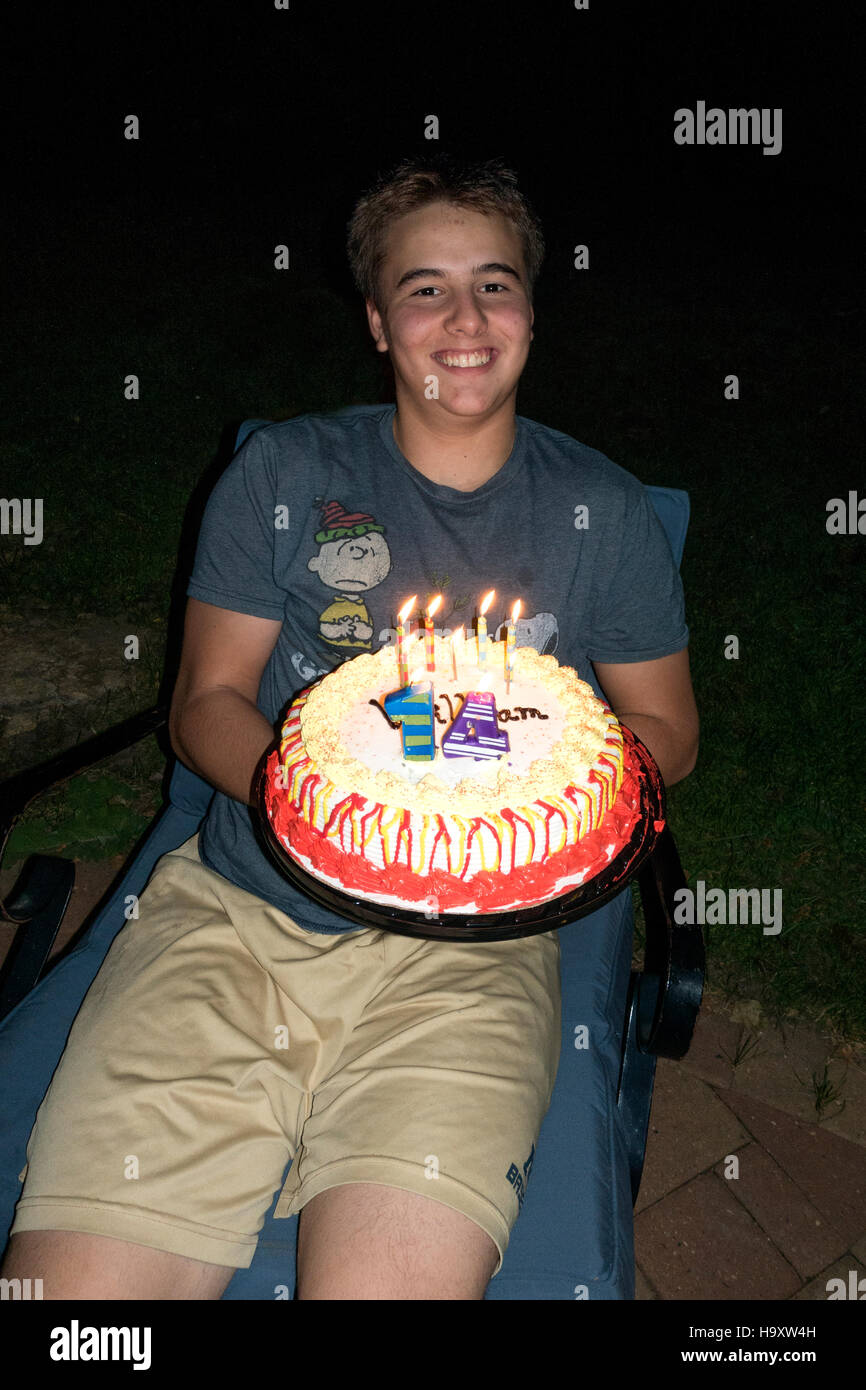 Ragazzo adolescente tiene il suo anno 14 Buon compleanno torta con candele accese. St Paul Minnesota MN USA Foto Stock