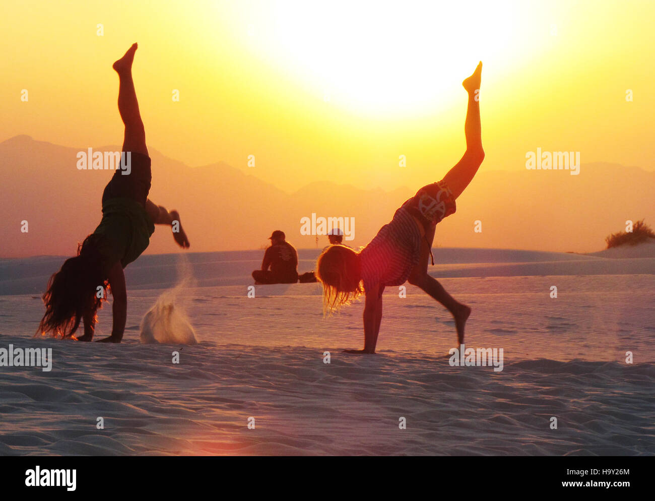 Un'immagine che cattura una persona che esegue ruote motrici al tramonto, enfatizzando la bellezza delle attività all'aperto in ambienti naturali. La scena mette in evidenza la gioia del movimento fisico e la connessione tra uomo e natura. Foto Stock Un'immagine che cattura una persona che esegue ruote motrici al tramonto, enfatizzando la bellezza delle attività all'aperto in ambienti naturali. La scena mette in evidenza la gioia del movimento fisico e la connessione tra uomo e natura. Foto Stock