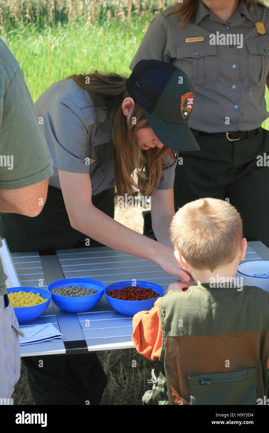 Nel Badlands National Park, Youth Intern Kelly assiste un bambino con attività artigianali presso l'Outdoor Campus - West di Rapid City. Questo evento fa parte dei programmi educativi del parco, che si concentrano sull'coinvolgere i bambini in attività legate alla natura e sulla promozione della consapevolezza ambientale. Foto Stock