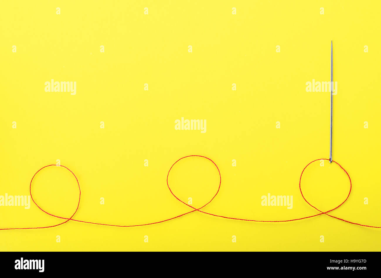 Filo rosso e ago su sfondo giallo, simbolo di fatto a mano e ricamo. Copyspace Foto Stock