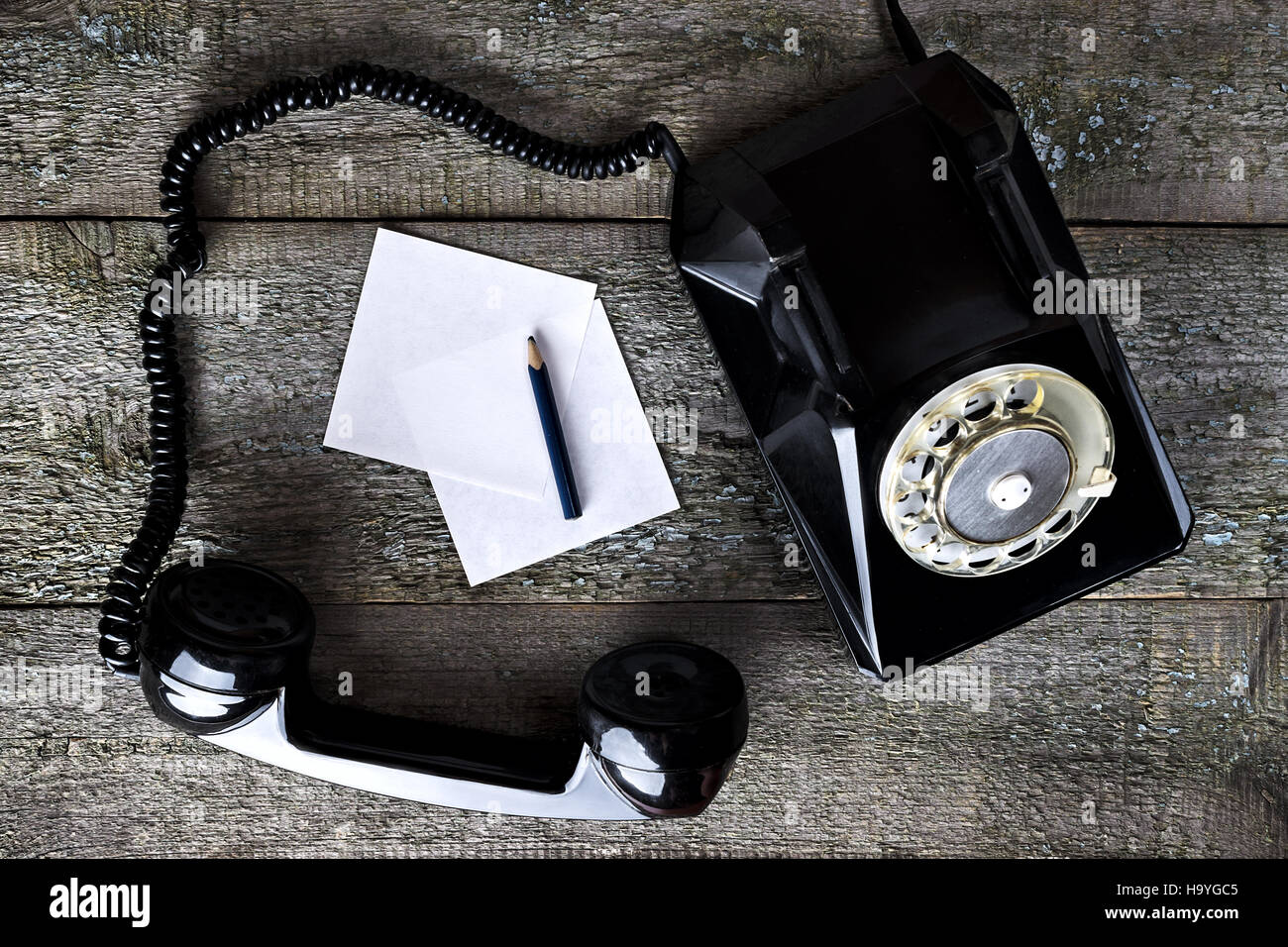 Nero telefono vintage su sfondo di legno con la matita di close-up, vista dall'alto, sollevare il telefono Foto Stock