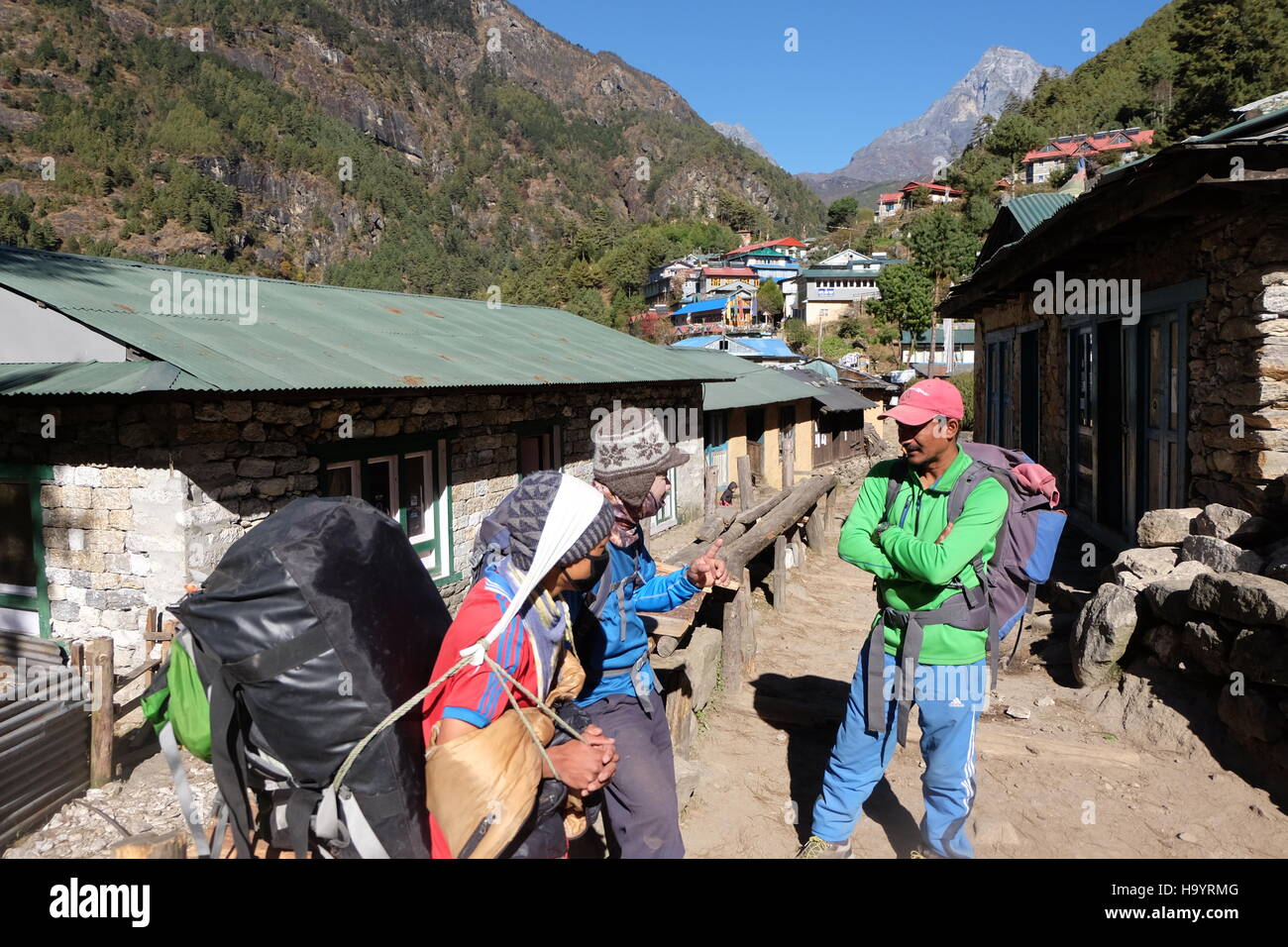 Una guida e dei facchini parlare durante una sosta lungo il campo base Everest trek, Nepal Foto Stock