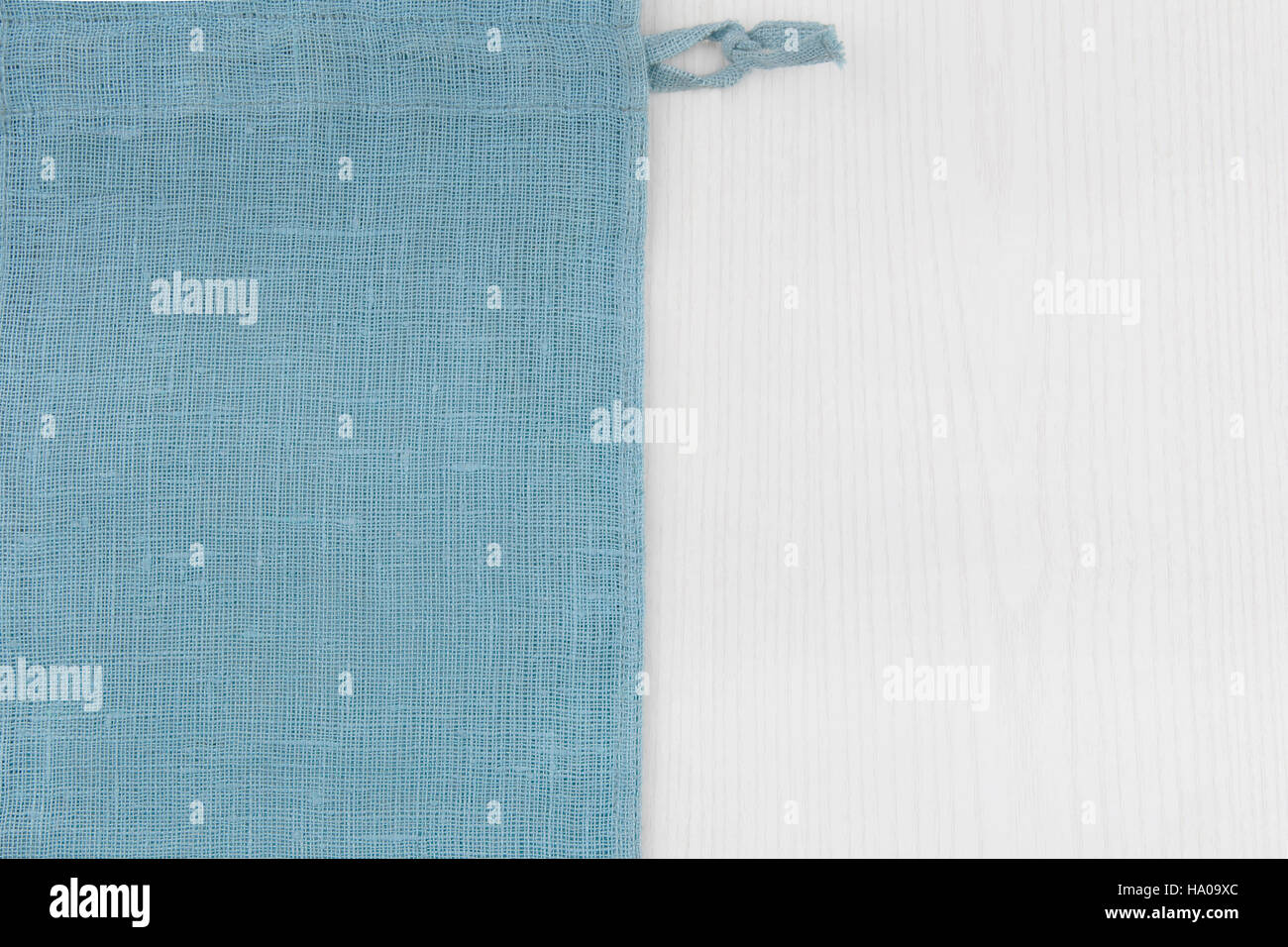 Sacco dal lato sinistro del bianco tavolo in legno.morbido blu tessuto tessuto di lino texture / legno texture. Grossi sacchi di iuta. Vista dall'alto. Foto Stock