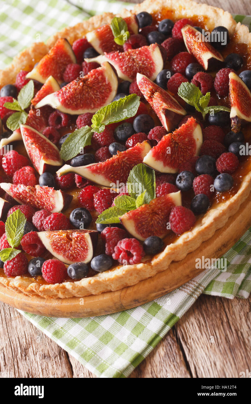 Crostata con fichi, lamponi e mirtilli macro sul tavolo. In verticale Foto Stock