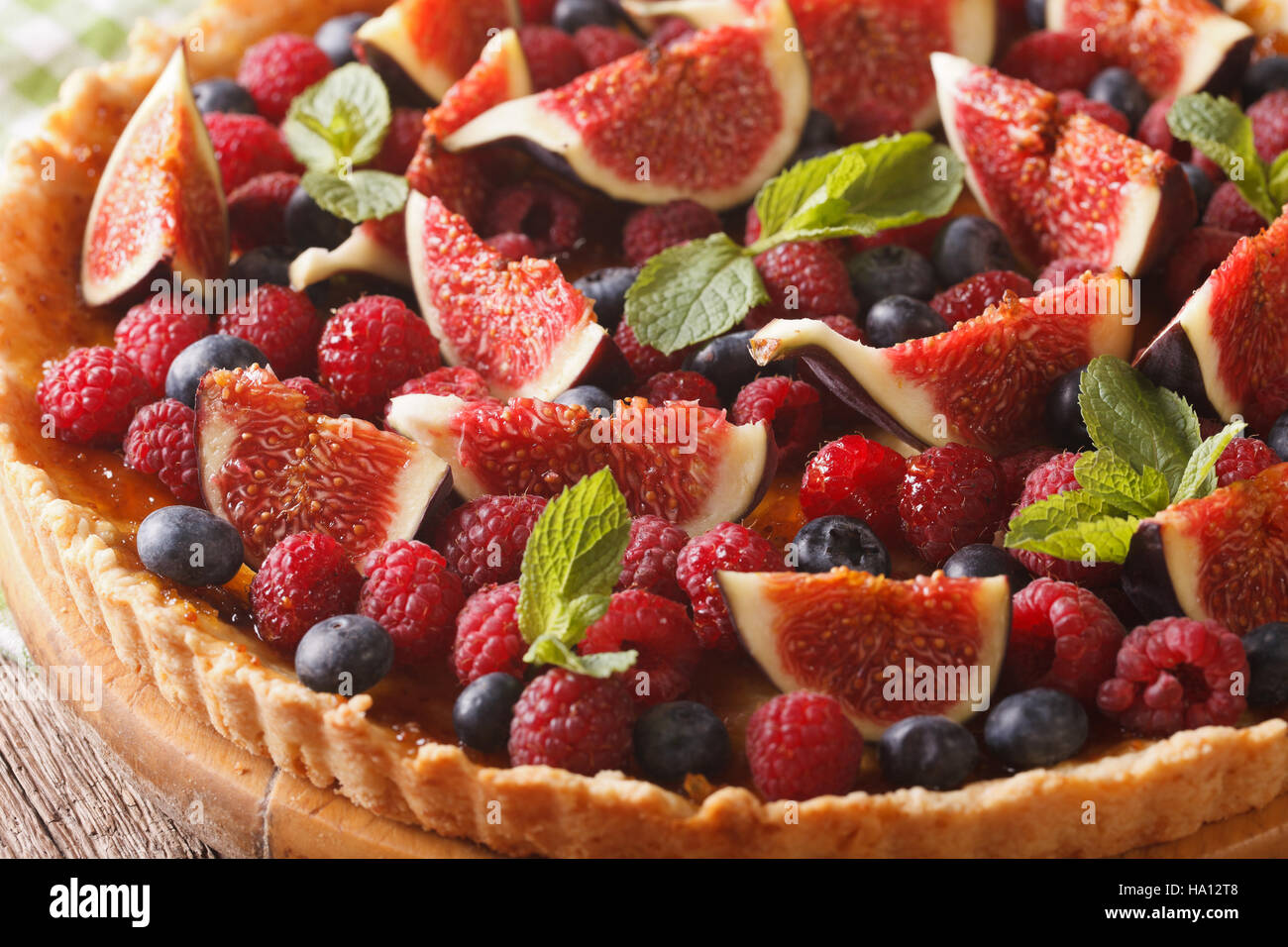 Crostata con fichi freschi, lamponi e mirtilli macro sul tavolo orizzontale. Foto Stock