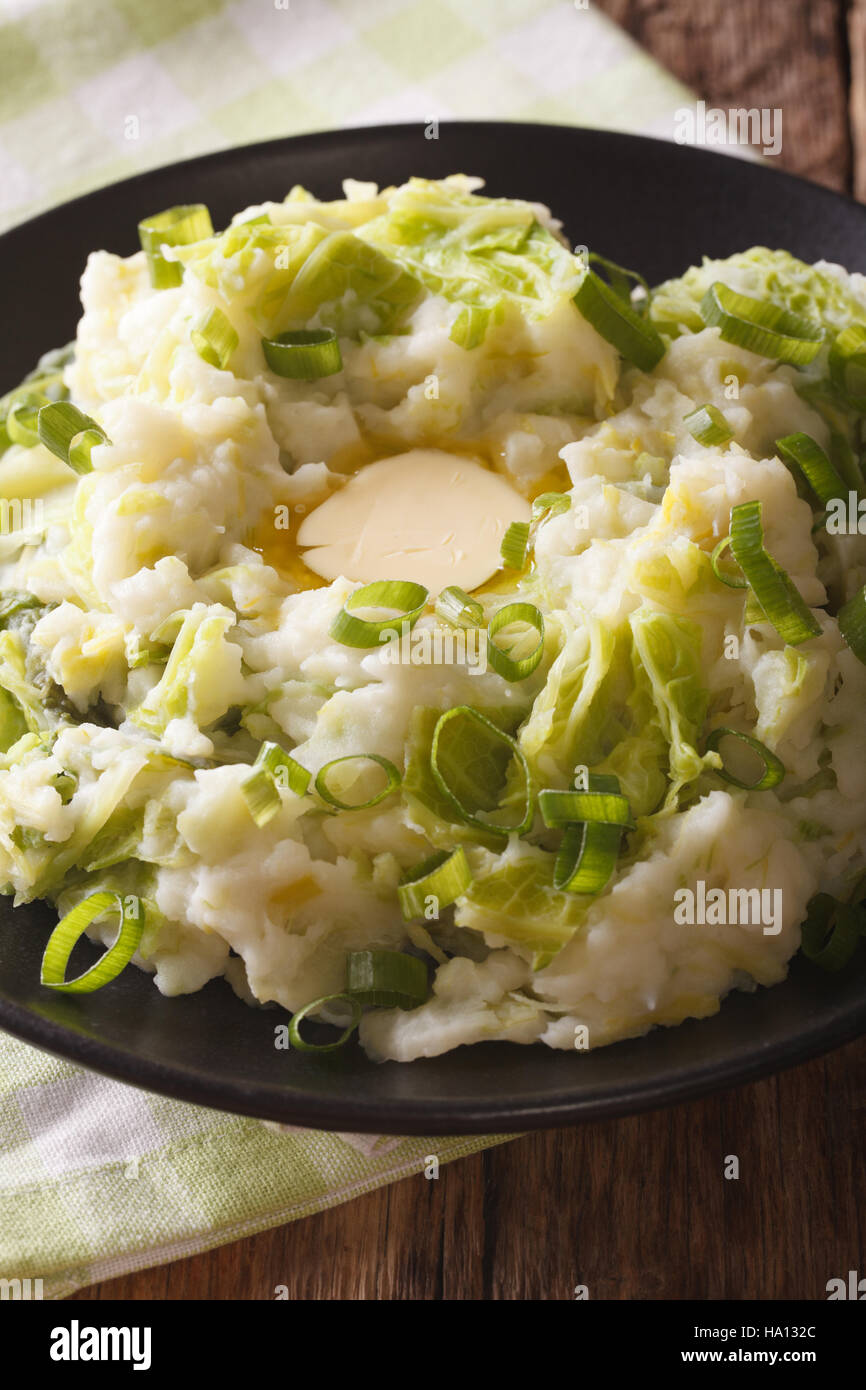 Fatti in casa di patate irlandese Colcannon con verdi e burro su una piastra macro. In verticale Foto Stock