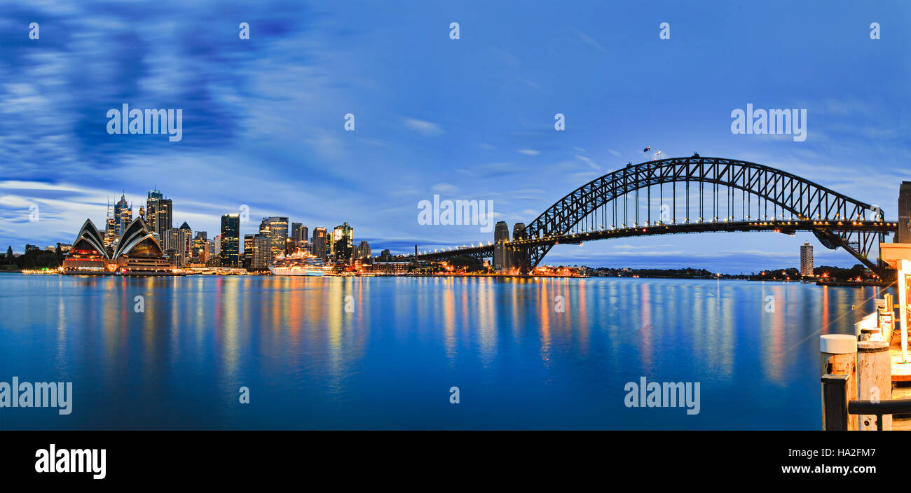 I punti di riferimento della città di Sydney CBD attraverso Harbour con bridge, Circular Quay, terminale passeggeri e il centro cittadino di grattacieli di Kirribilli pier al blue nuvoloso Foto Stock
