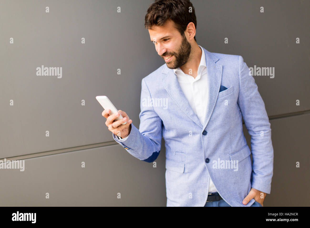 Imprenditore con un telefono dal muro nero Foto Stock