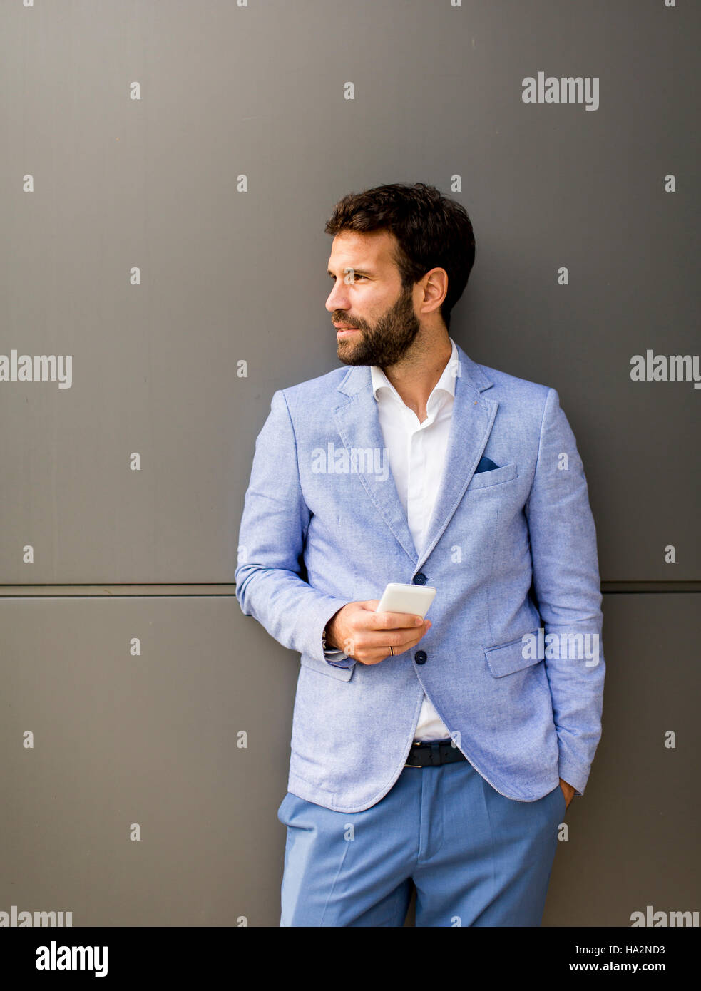 Imprenditore con un telefono dal muro nero Foto Stock