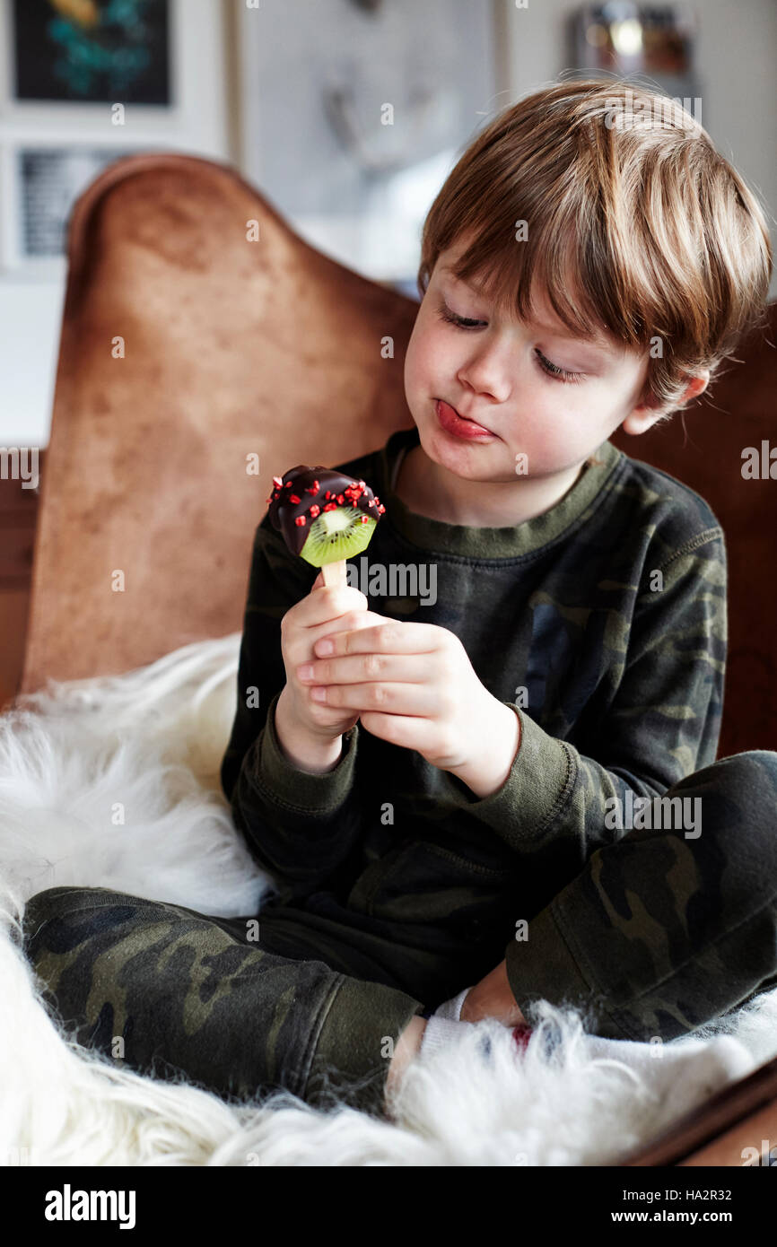 Ragazzo seduto nella sedia mangiar sano trattare Foto Stock