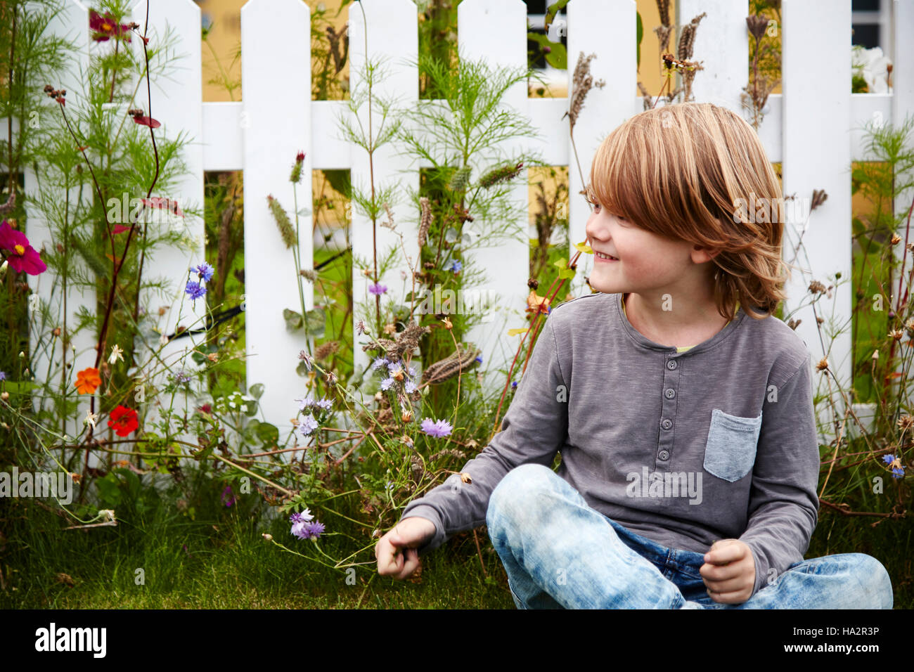 Sorridente ragazzo seduto in un giardino Foto Stock