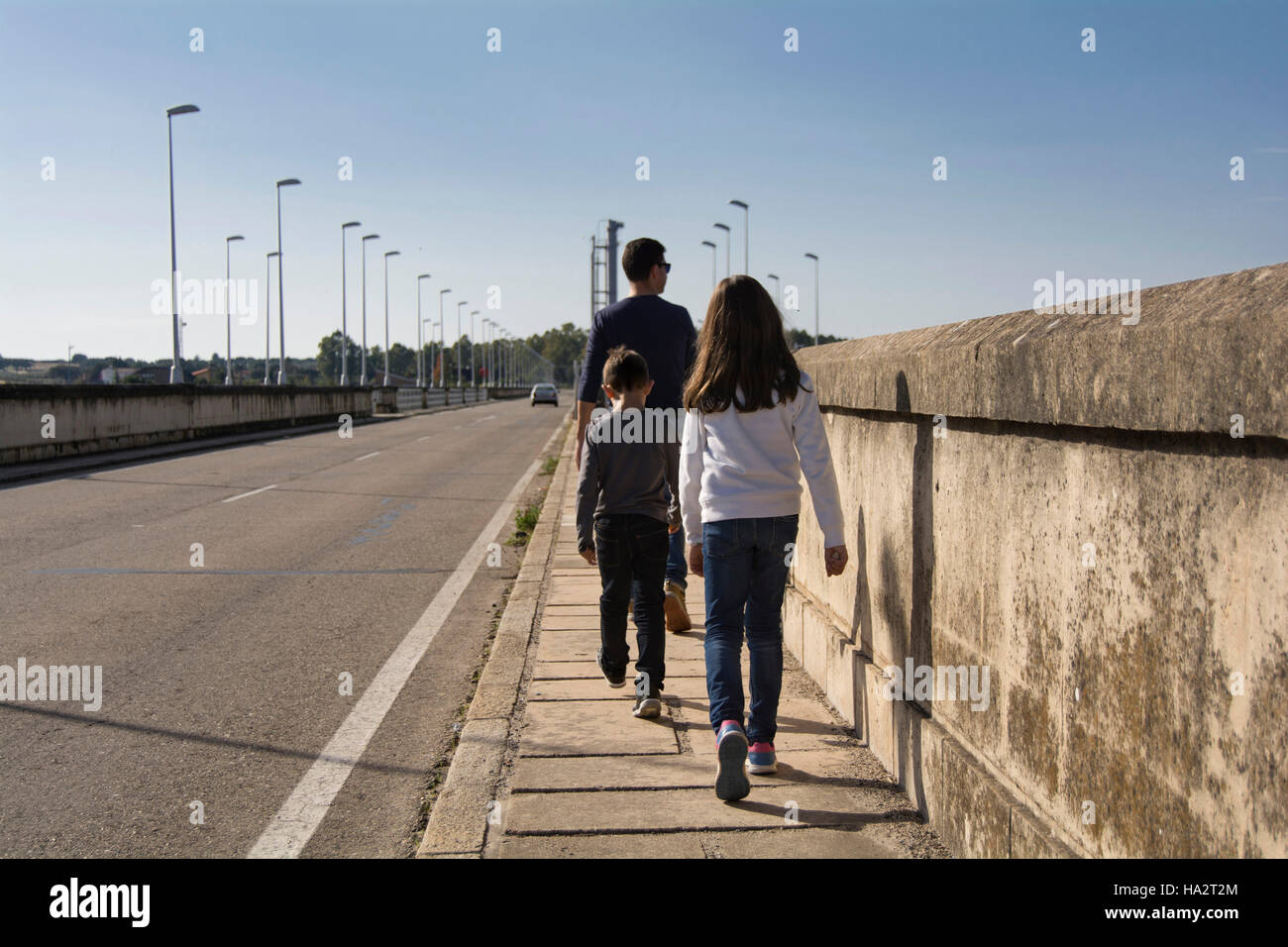 Padre e due figli che camminano giù street Foto Stock