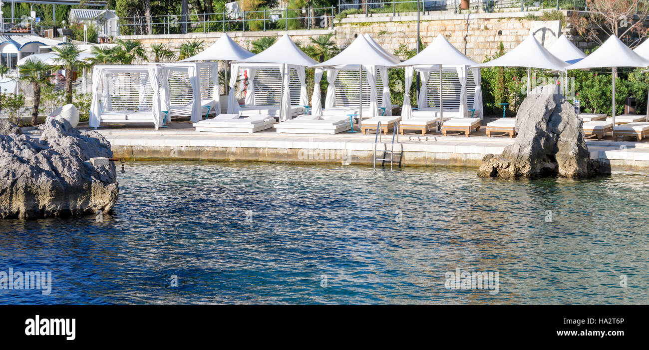 Resort di lusso spiaggia privata con letti, materassi e ombrelloni bianchi Foto Stock
