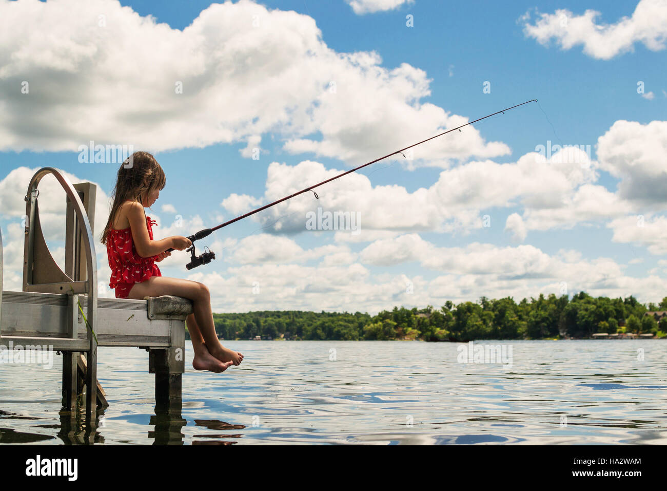 Ragazza seduta sulla pesca del dock Foto Stock