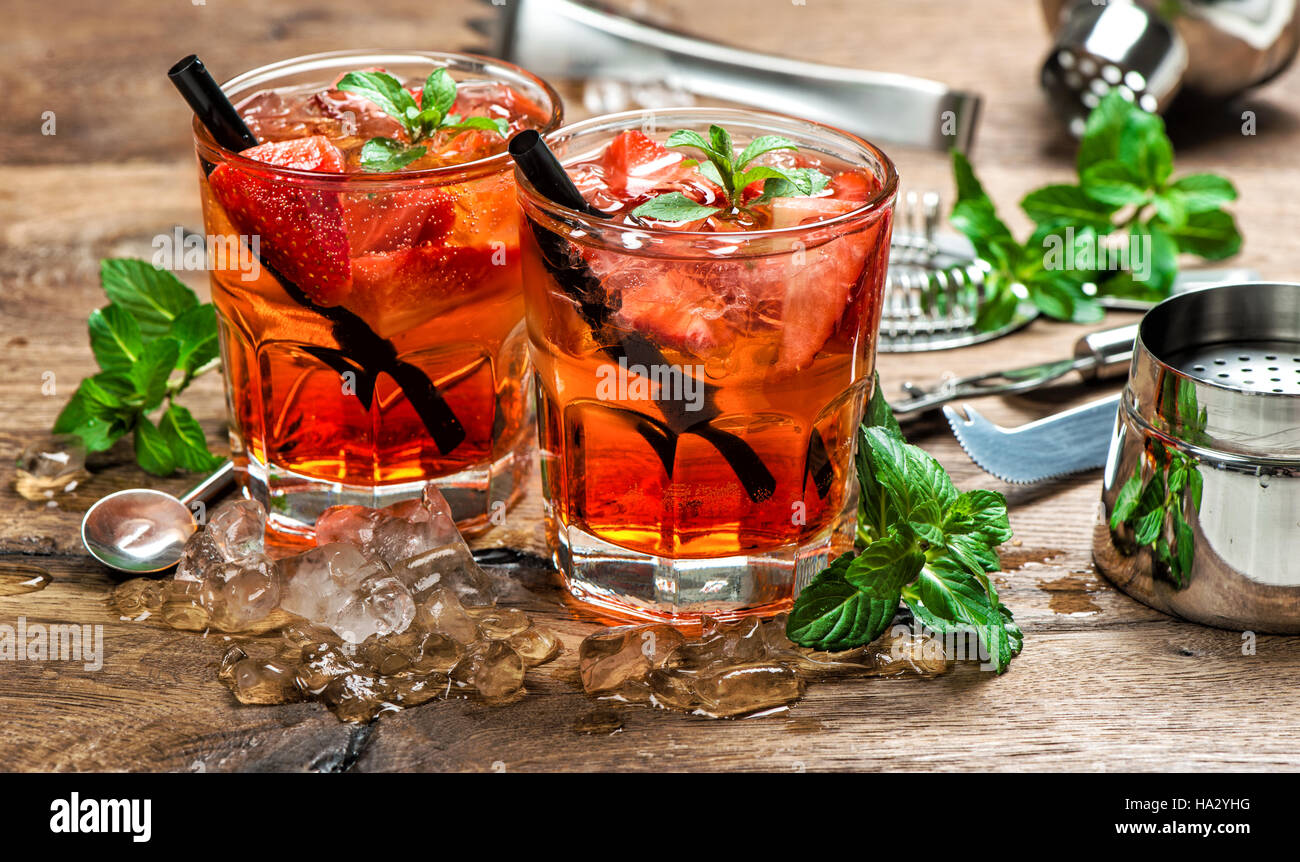Red drink con ghiaccio e succo di frutta. Aperitivo. Cocktail bar rendendo gli strumenti, fragola, foglie di menta Foto Stock