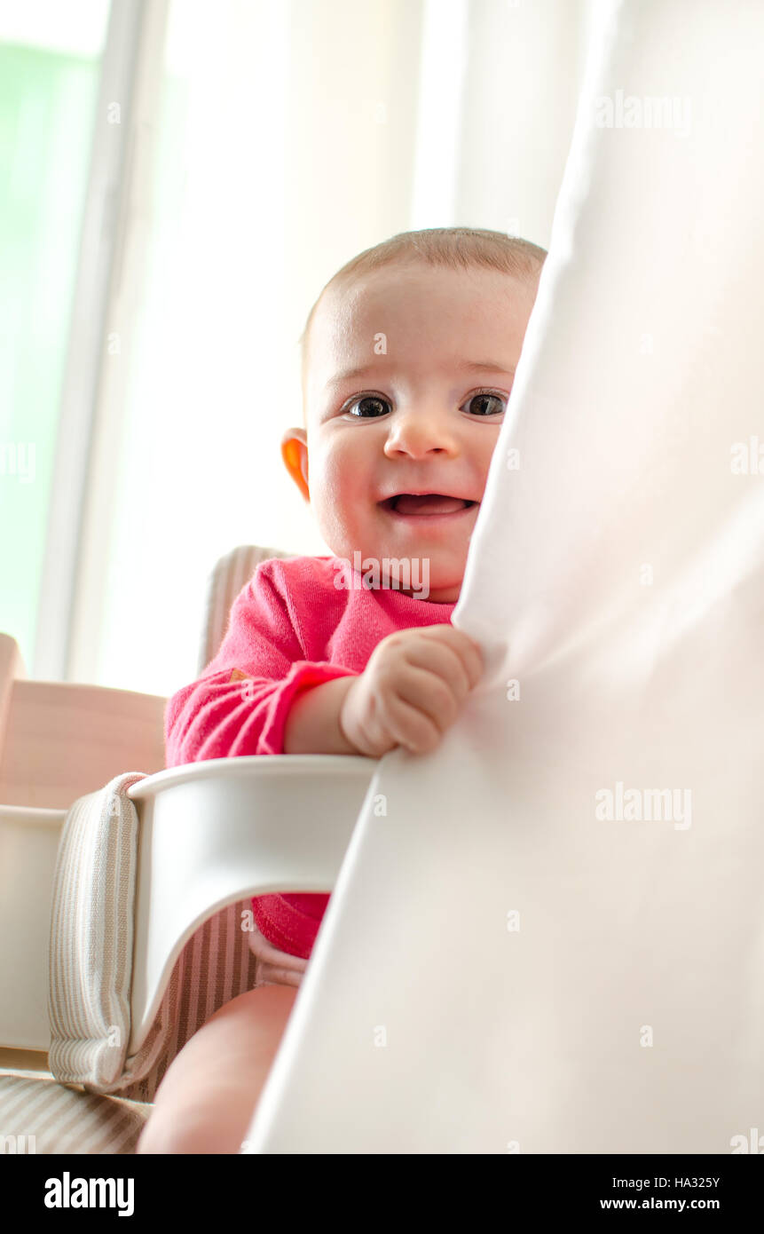 Il bambino tende a nascondere giocoso sorriso neonato Foto Stock