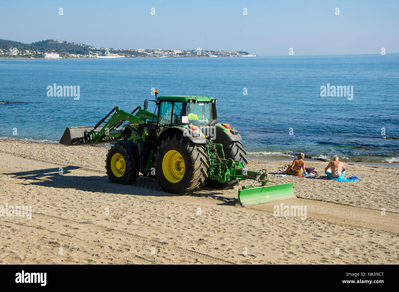 Due turisti sulla spiaggia vicino il trattore Renourishment, restauro, rifornimento opere di sabbia a La Cala, Mijas, Spagna. Foto Stock