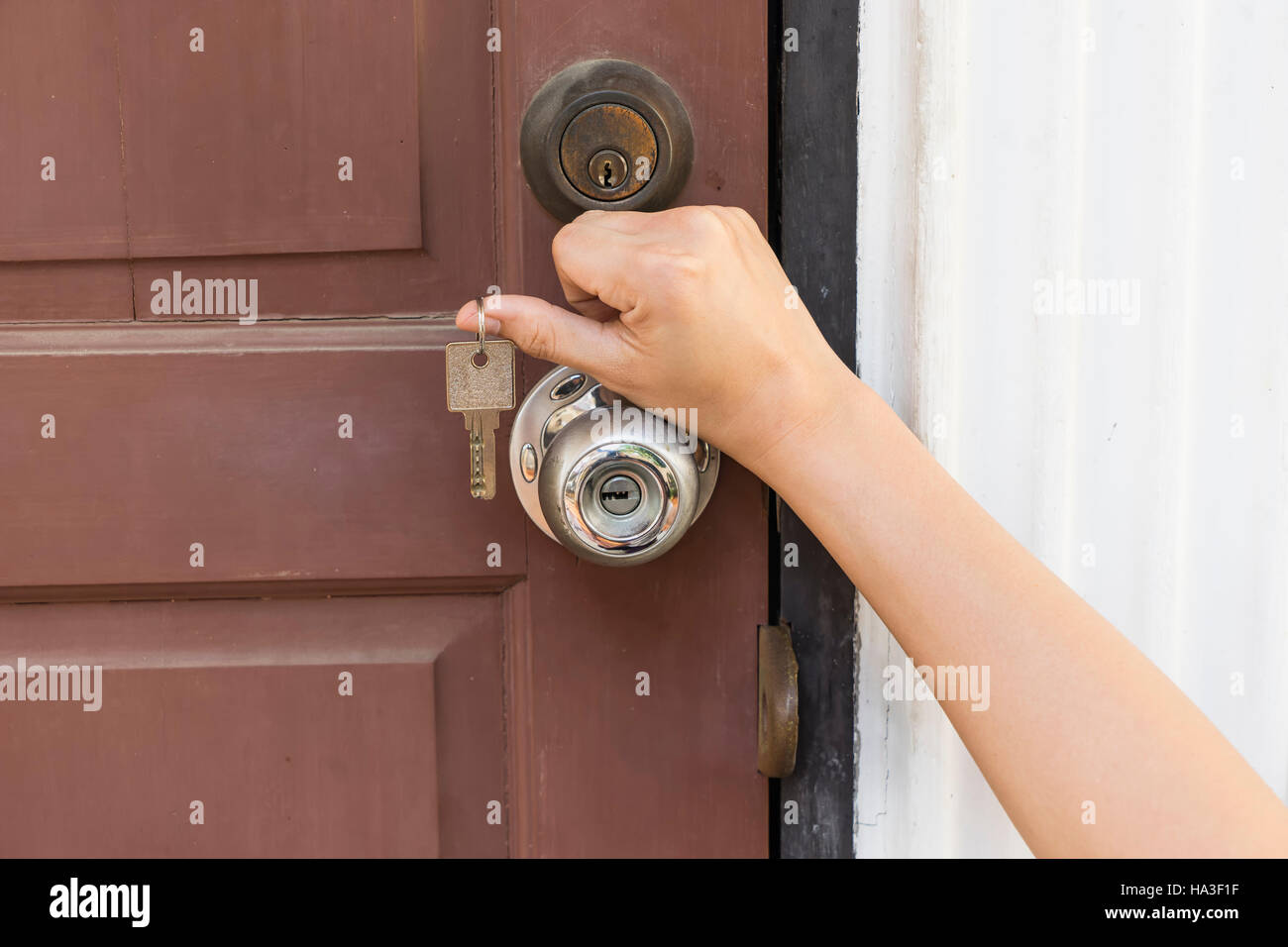 La chiave di casa in mano la ragazza e la vecchia porta di legno per aprire - si può utilizzare per visualizzare o montaggi sul prodotto Foto Stock