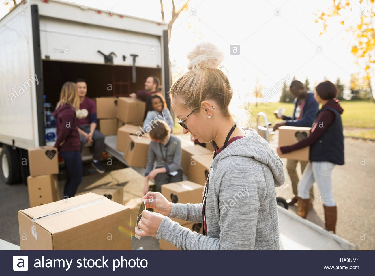 Donna volontariato lo scarico di scatole di cartone dal carrello Foto Stock