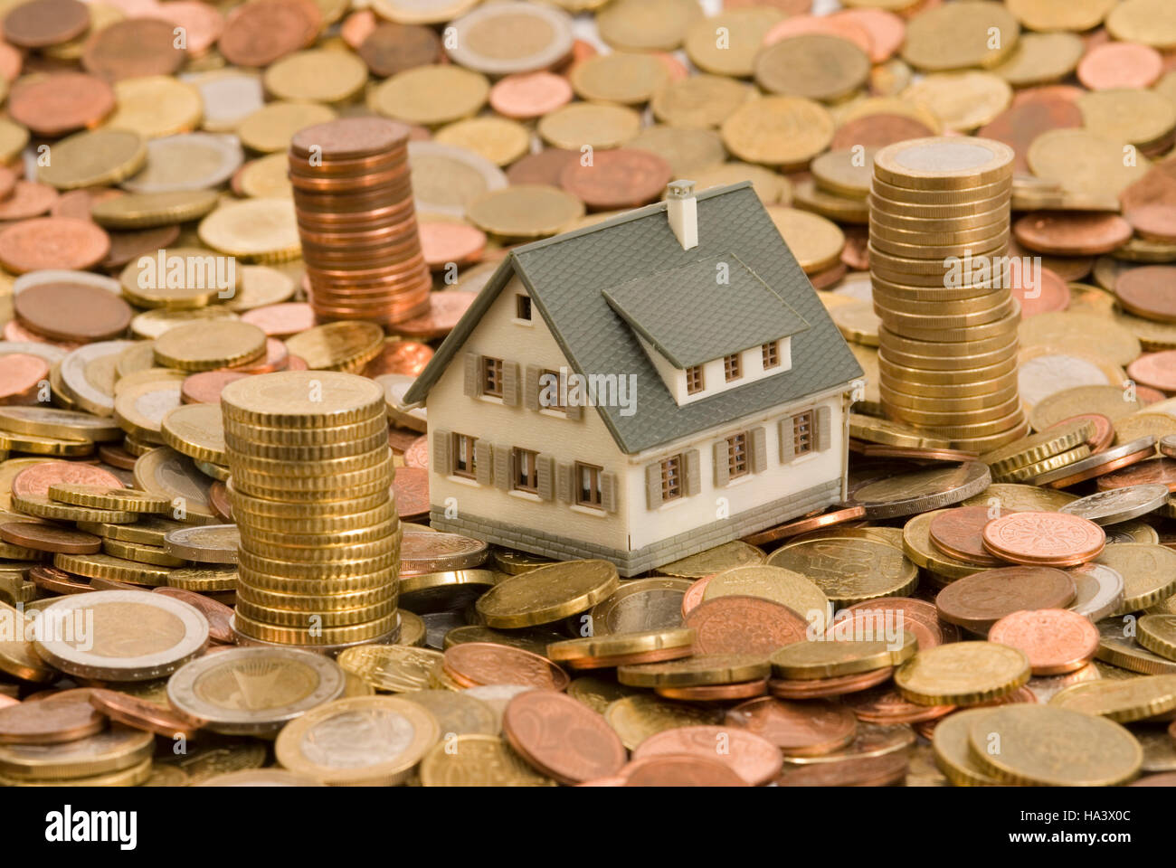 Casa in miniatura sulle monete, immagine simbolica per casa e finanze Foto Stock