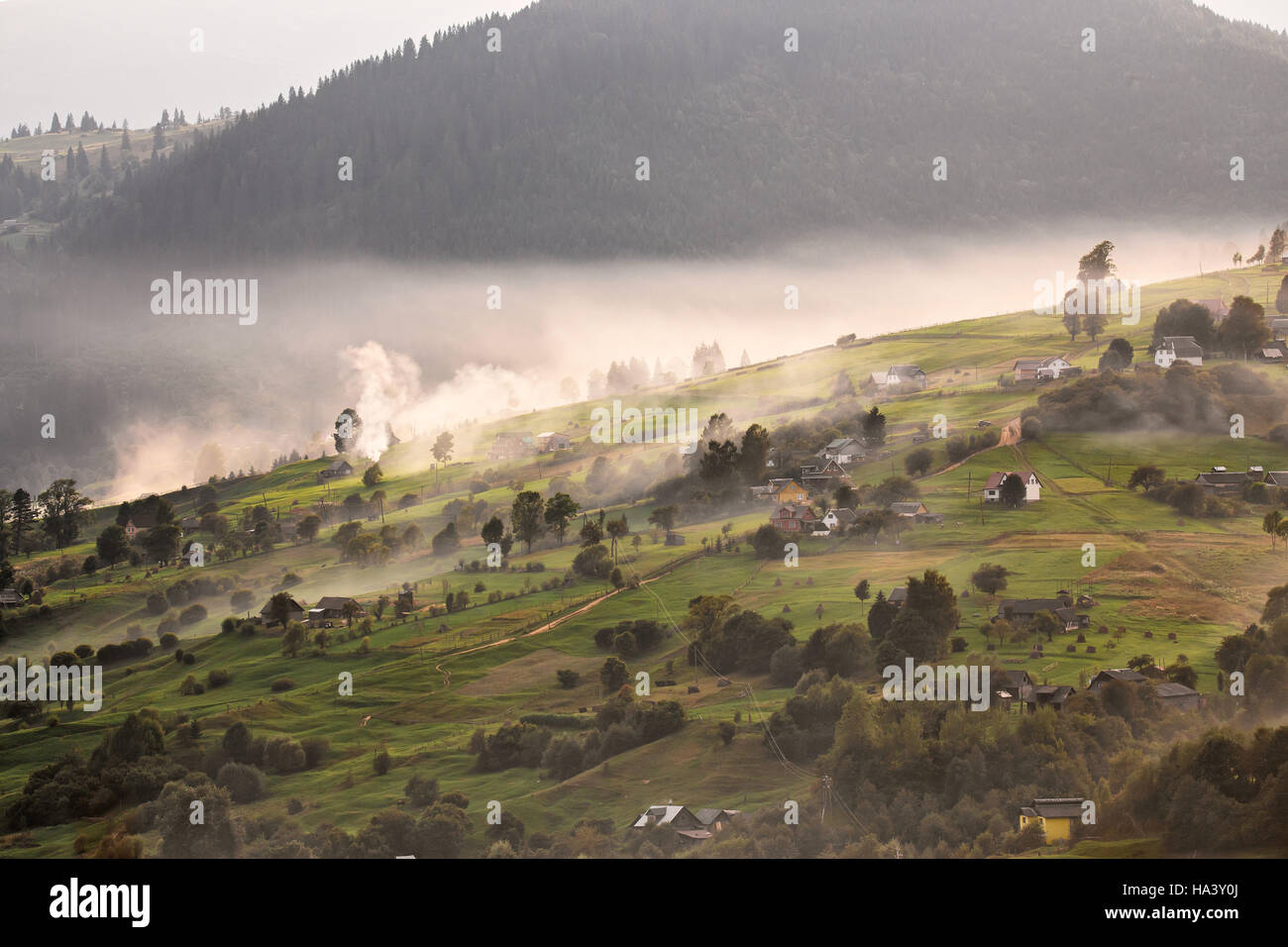 Villaggio alpino in montagna. Fumo, falò e haze sulle colline nei Carpazi. Foto Stock