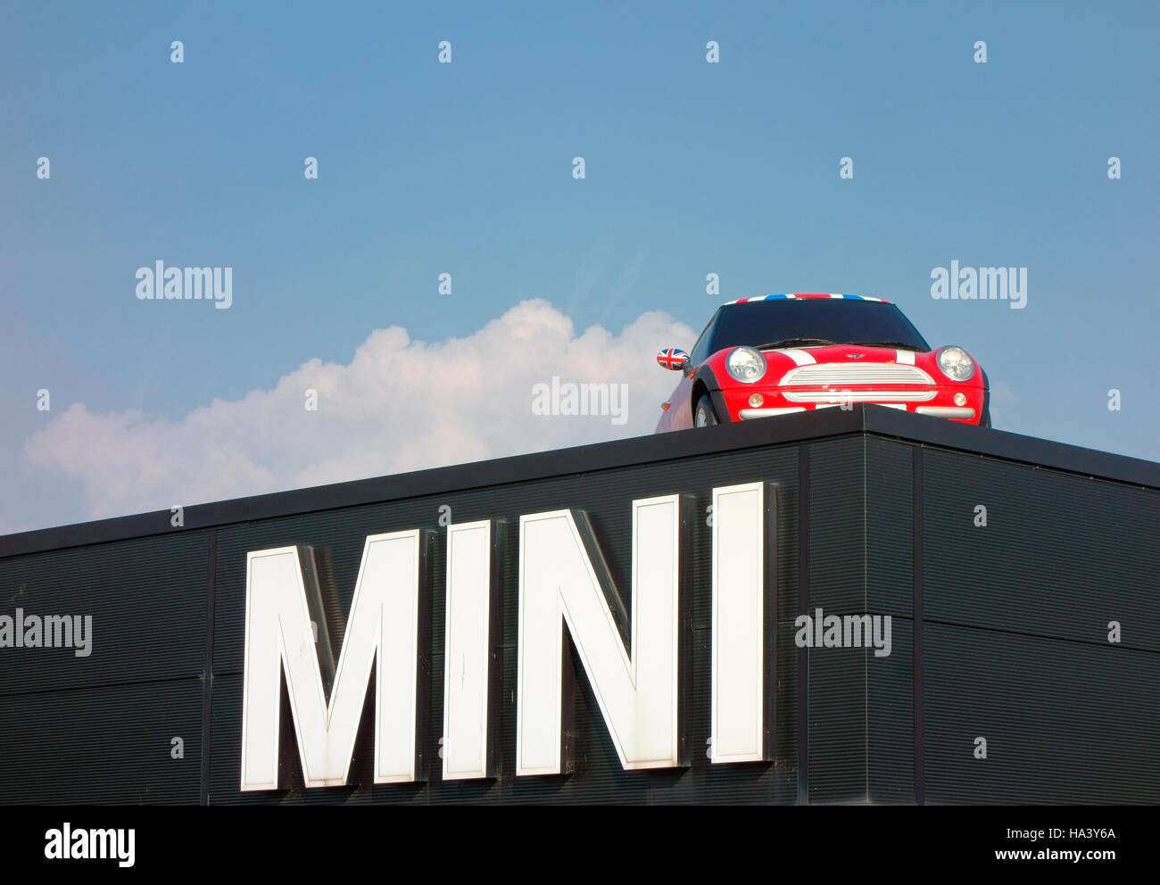 Mini auto su un tetto sopra gigante segno mini Foto Stock