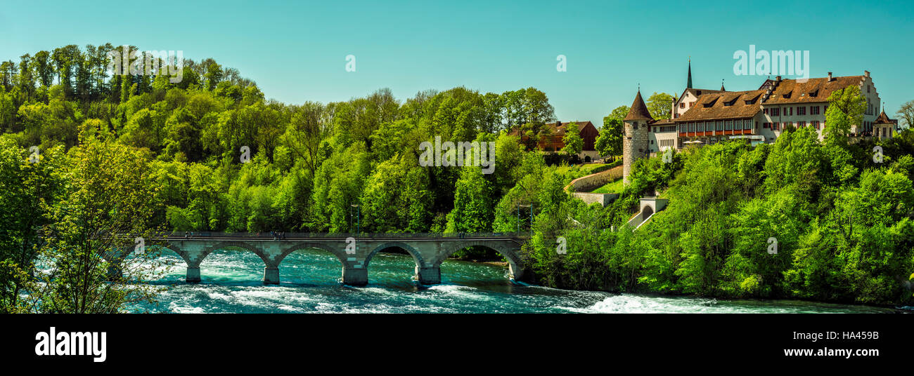 Panorama in una giornata di sole con il Laufen Castello circondato da una foresta e un ponte di pietra sul fiume Reno, nella città Laufen-Uhwiesen, Svizzera Foto Stock