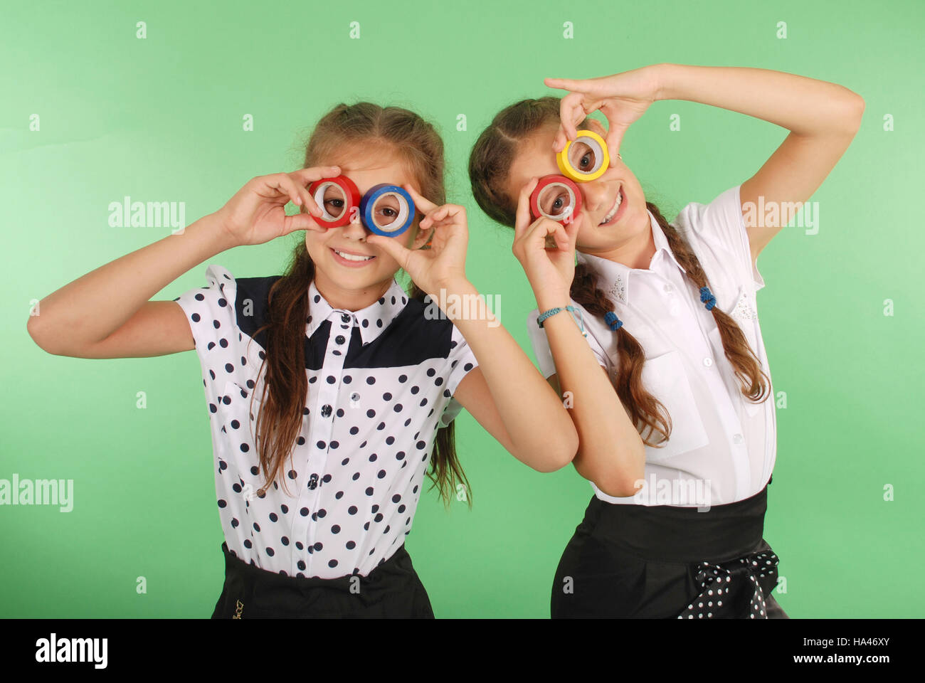 Due belle scuola ragazza con due nastri isolanti sugli occhi per guardare radiante su verde Foto Stock