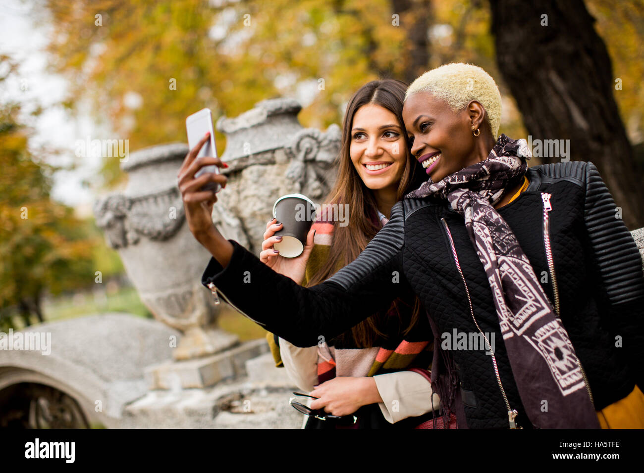 Giovane americano africano e caucasico donne tenendo selfie outdoor Foto Stock