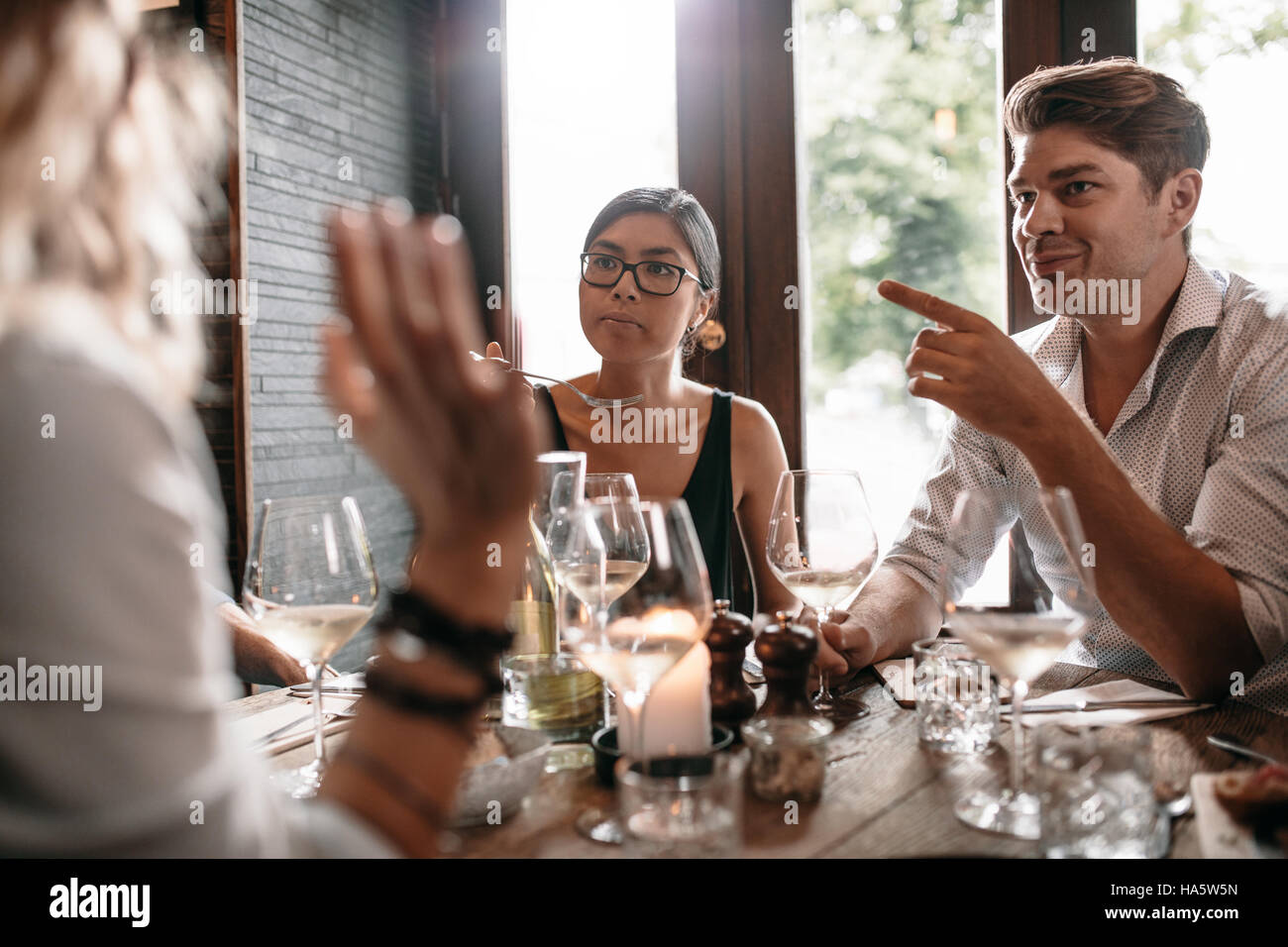 Gruppo di amici riuniti presso il ristorante per la cena. Giovani uomini e donne aventi pasto serale presso il cafe. Foto Stock