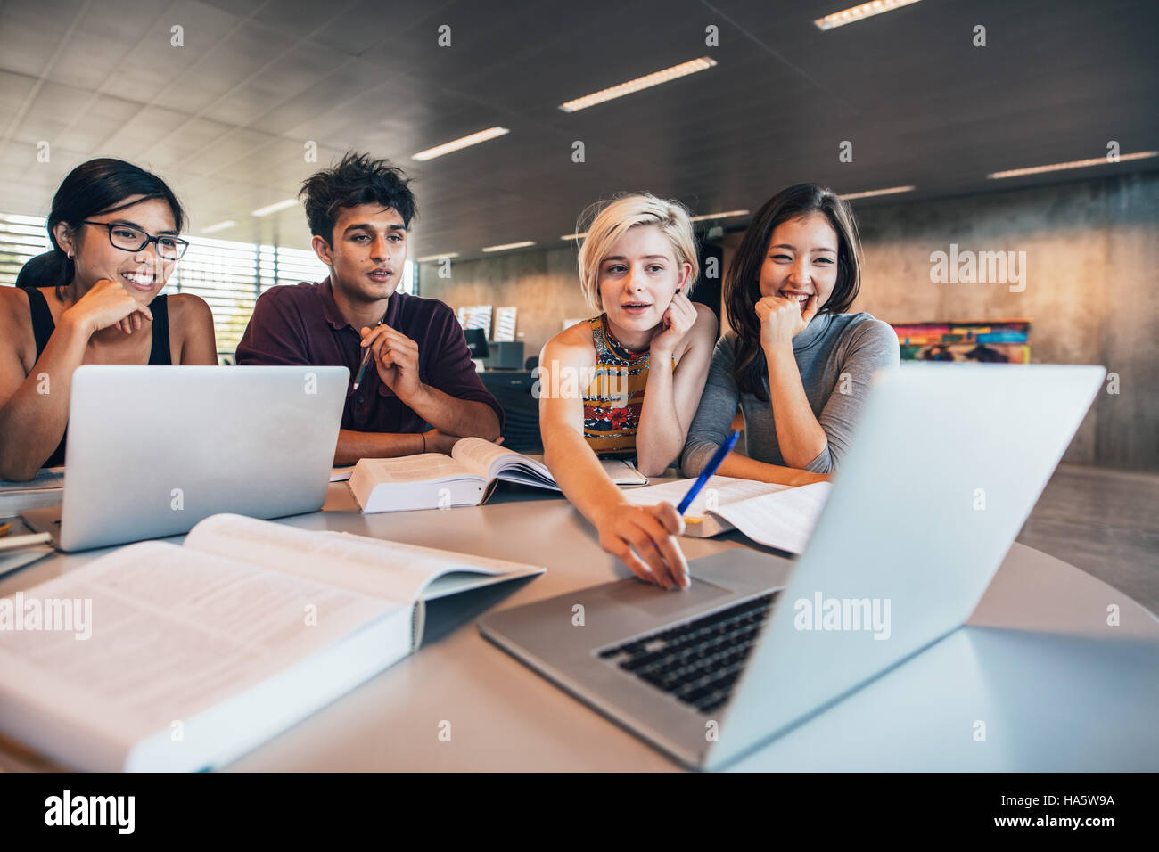 Gli studenti universitari utilizzando computer portatile mentre è seduto al tavolo. Gruppo di studio per la scuola di assegnazione. Foto Stock