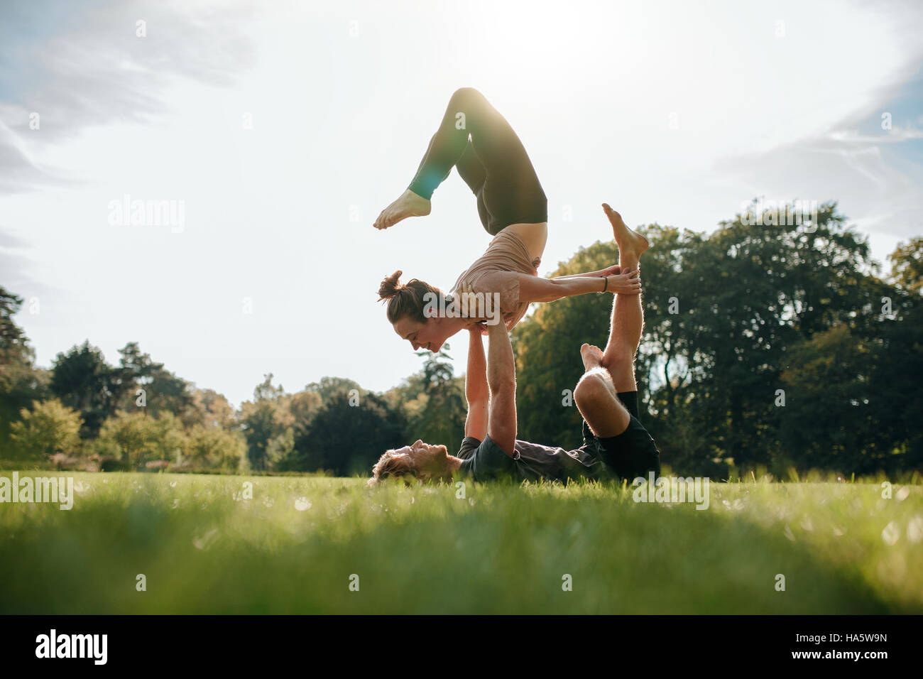 Coppia caucasica facendo acro yoga nel parco. L uomo e la donna facendo varie yoga pone in coppia all'esterno. Foto Stock