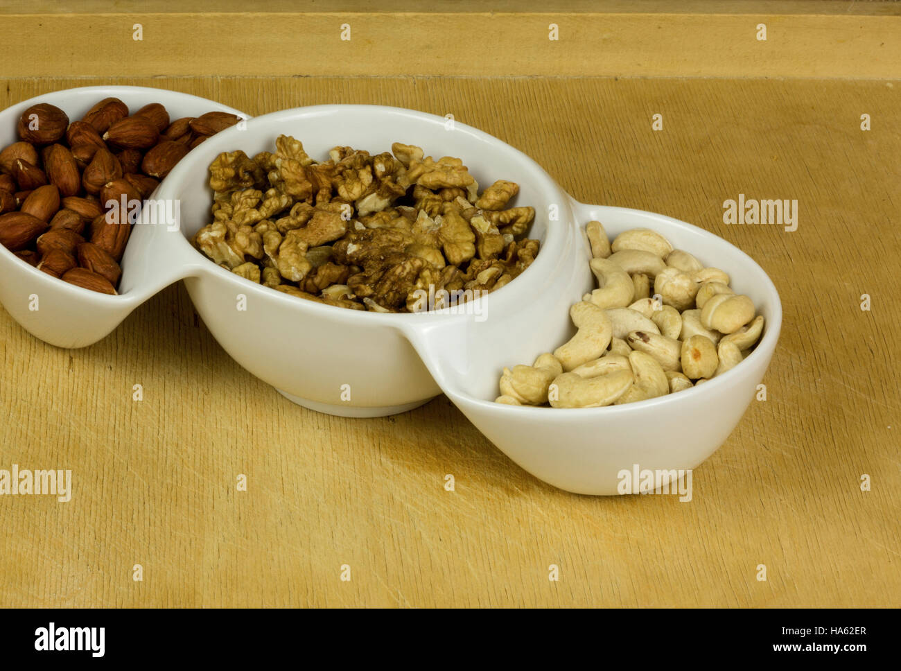 Tre tipi di dadi freschi ,Indian mandorle,(Macadamia) noci, nocciole in una ciotola bianco. Mangiare sano . Chiudere, vista orizzontale. Foto Stock