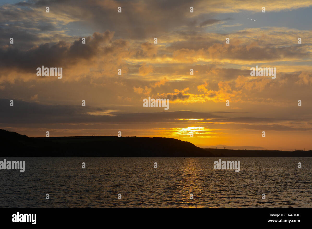 Golden sunrise sky con le nubi sulla terra con la riflessione nella calma golden sea Foto Stock
