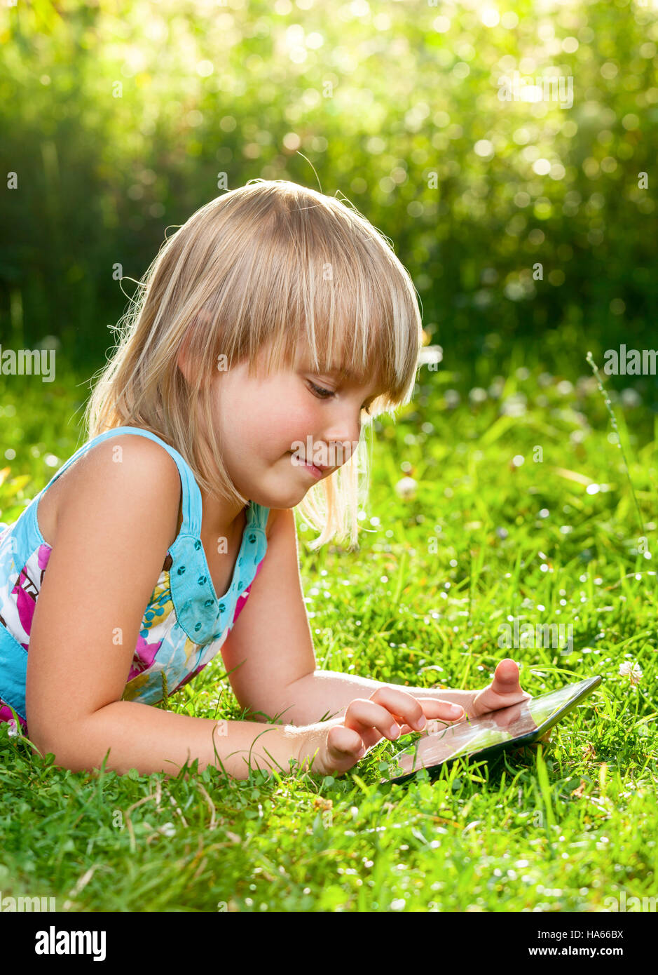Bambina con un touch pad in un giardino estivo Foto Stock