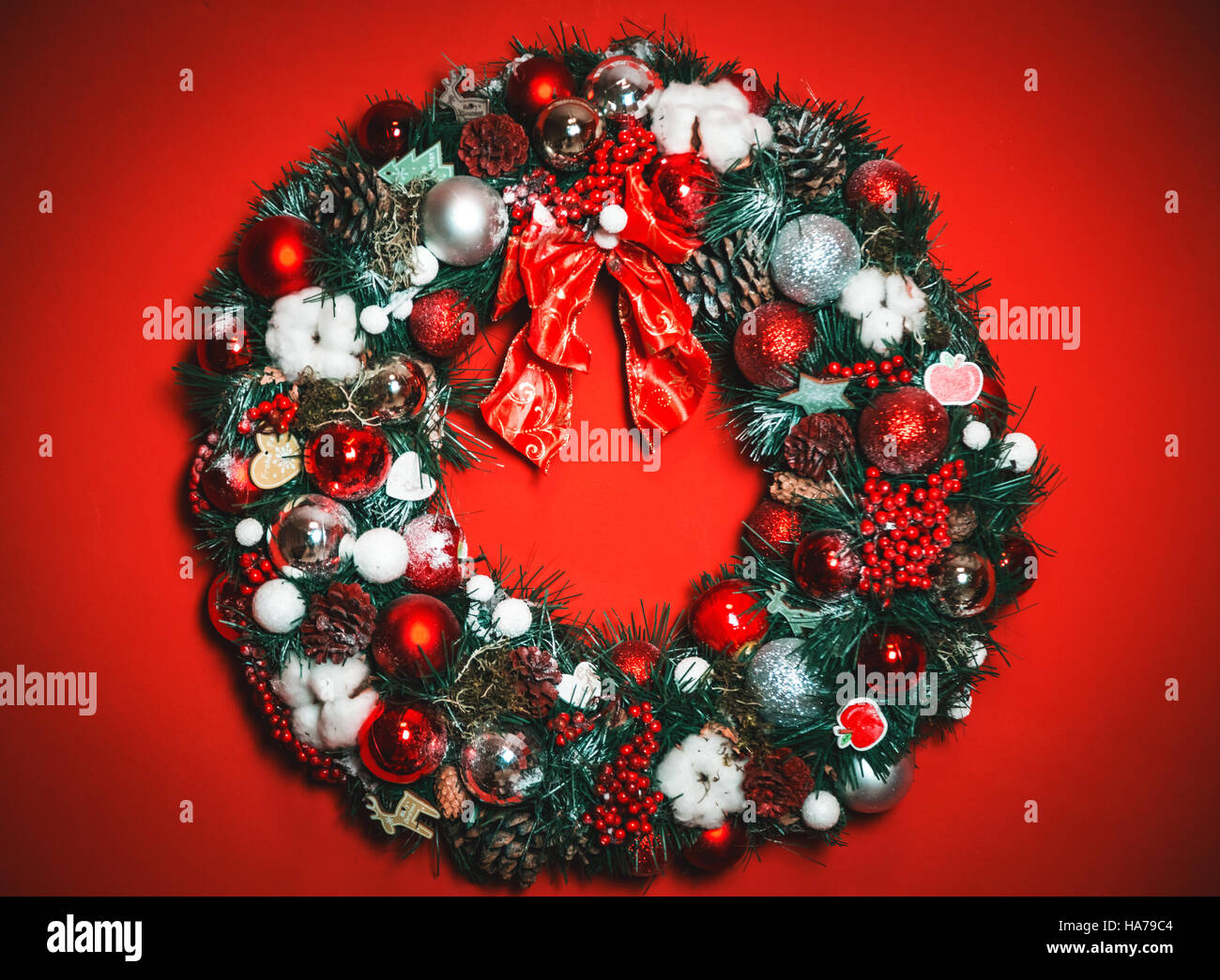 Bella ghirlanda di Natale con rami di abete e giocattoli su sfondo rosso Foto Stock