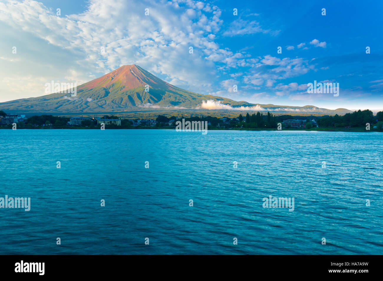 Il monte Fuji bagna nella mattina di luce laterale mentre il lago Kawaguchiko siede in ombra sotto nuvoloso cielo blu su un giorno di estate, cinque laghi Foto Stock