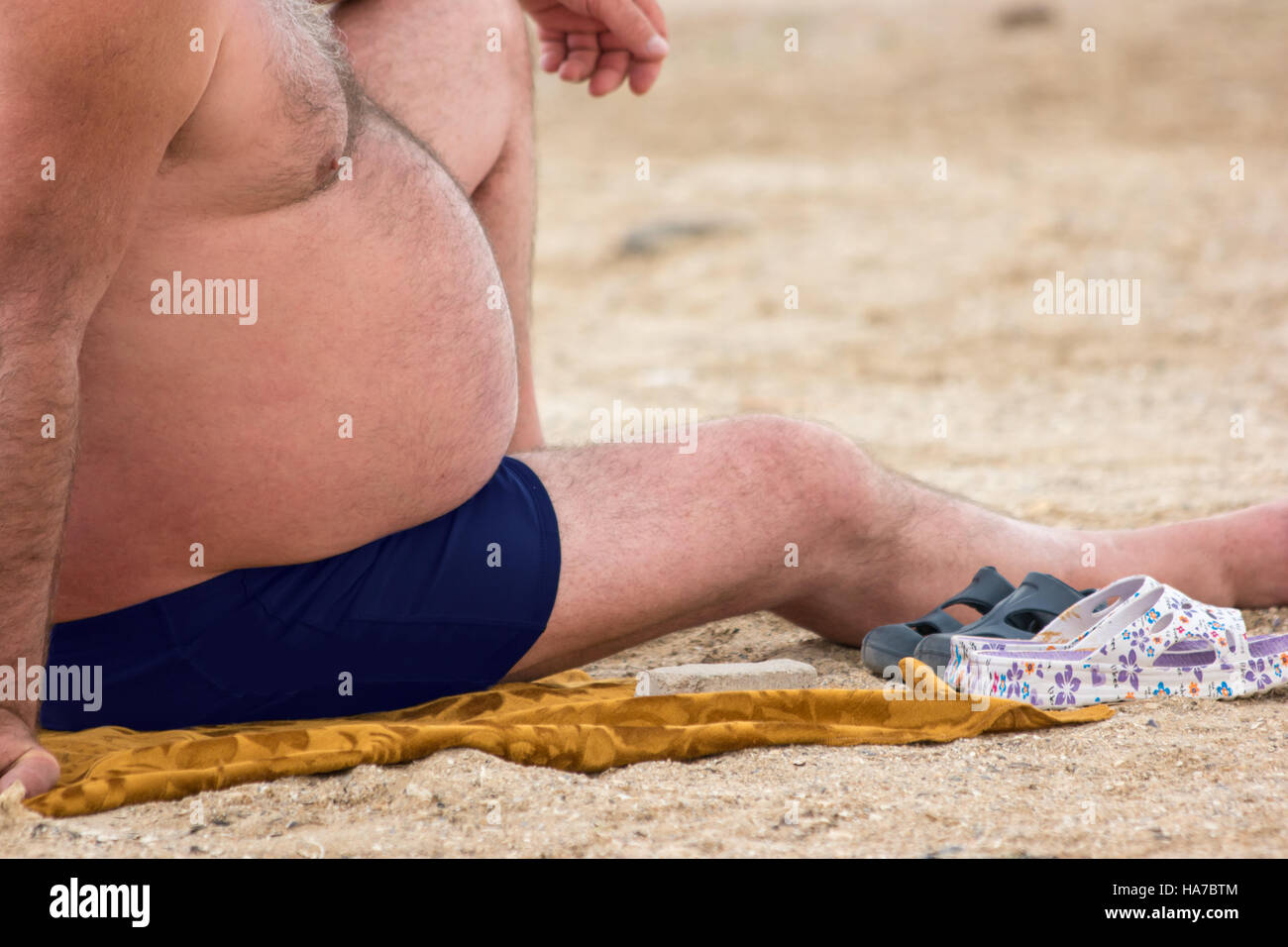 Il grasso ragazzo seduto sulla spiaggia. Foto Stock