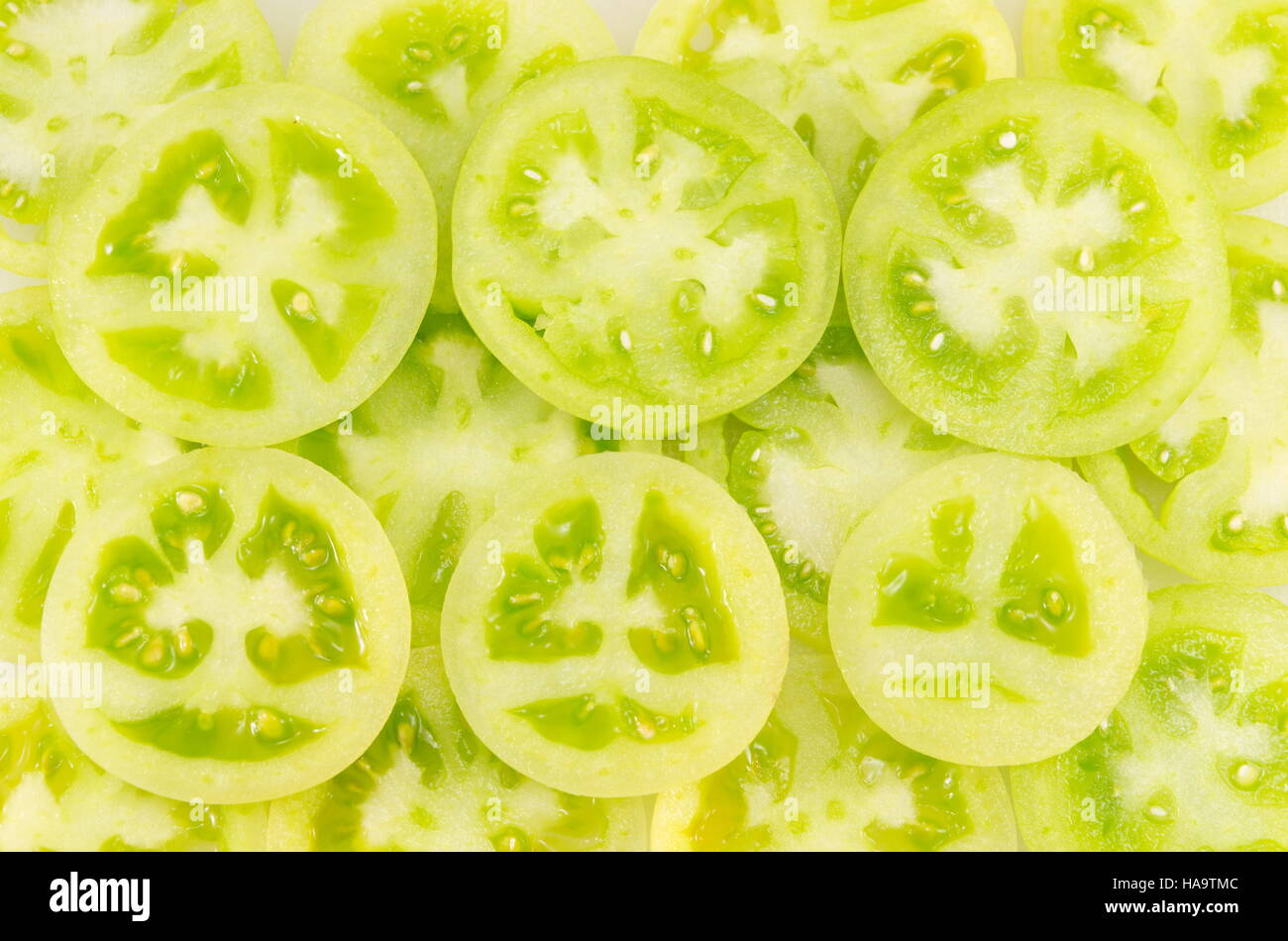 Pomodori verdi affettato in cerchi e disposti insieme accanto a un rosso fetta di pomodoro Foto Stock