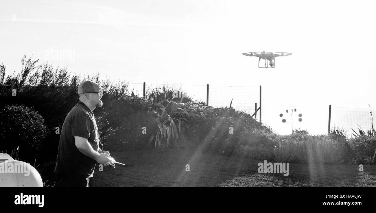 Un uomo vola un drone in una iarda posteriore Foto Stock