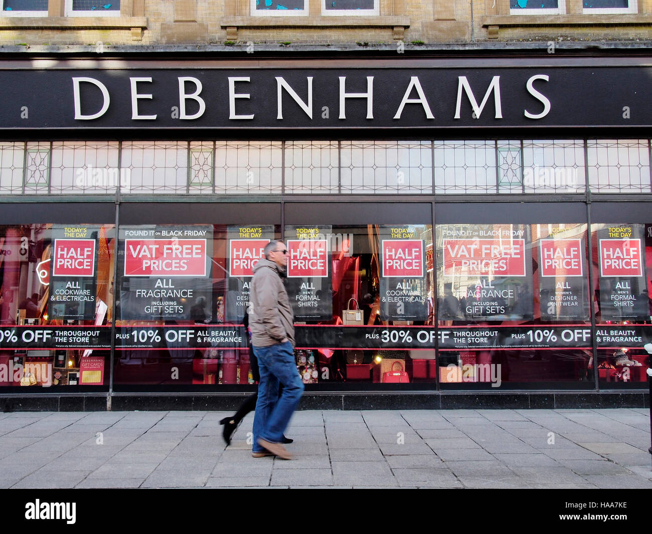 Un giovane a piedi passato un deserto negozio Debenhams con manifesti pubblicitari di riduzioni di prezzo durante il Black Friday sales 2016. Foto Stock