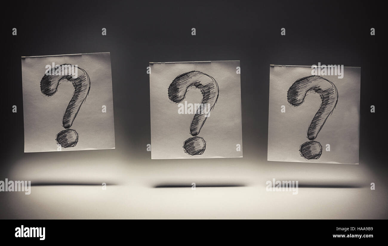 Un punto interrogativo disegnato su carta, su sfondo grigio. Foto Stock
