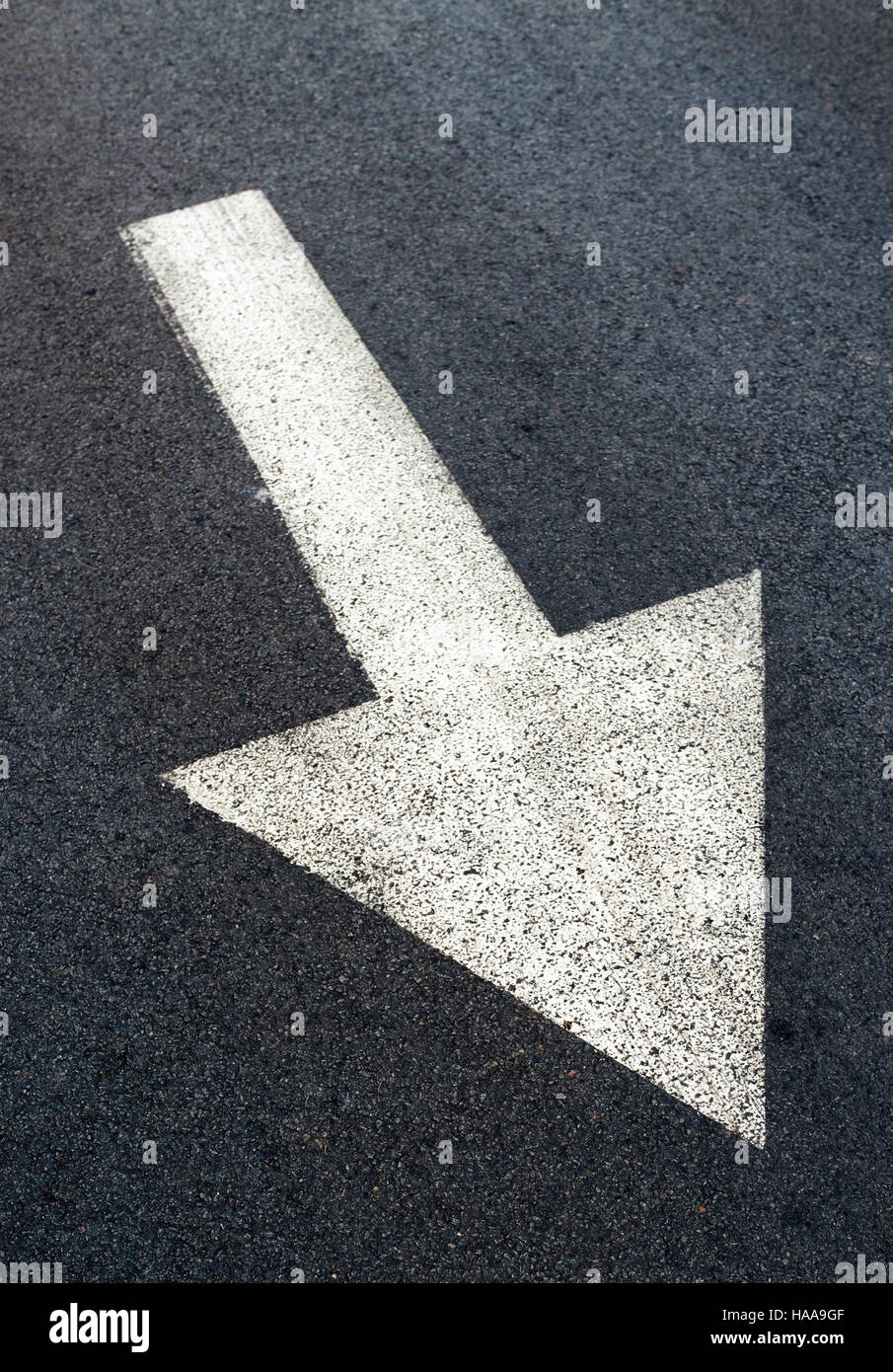 Freccia bianca sulla strada asfaltata, segno di traffico marcatura sulla carreggiata Foto Stock