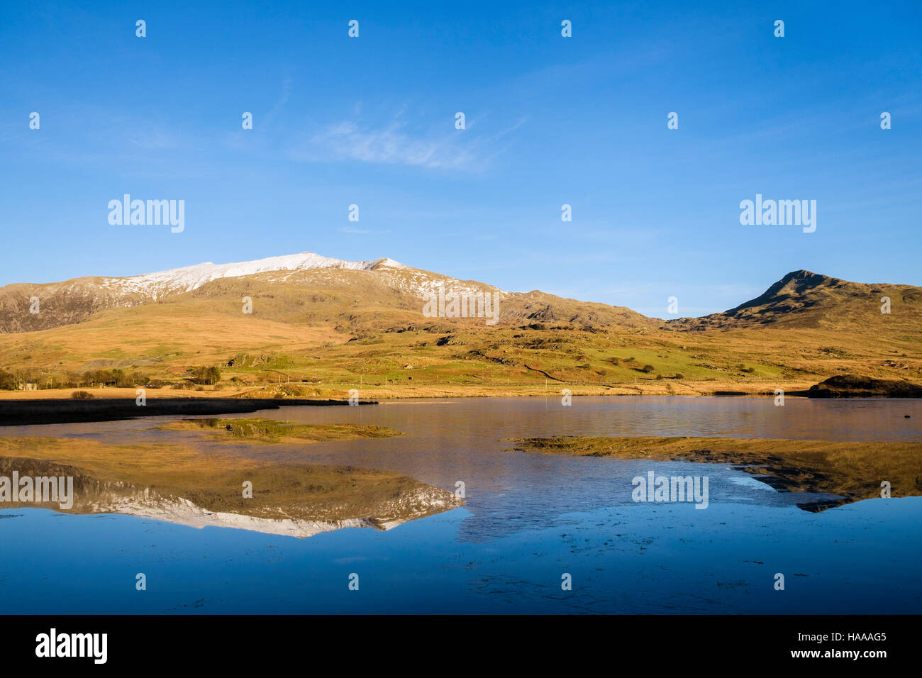 Cima innevata del Mount Snowdon e Yr Aran riflesso in acque calme della parte congelati Llyn y Gader nel Parco Nazionale di Snowdonia (Eryri). Rhyd-Ddu Wales UK Foto Stock