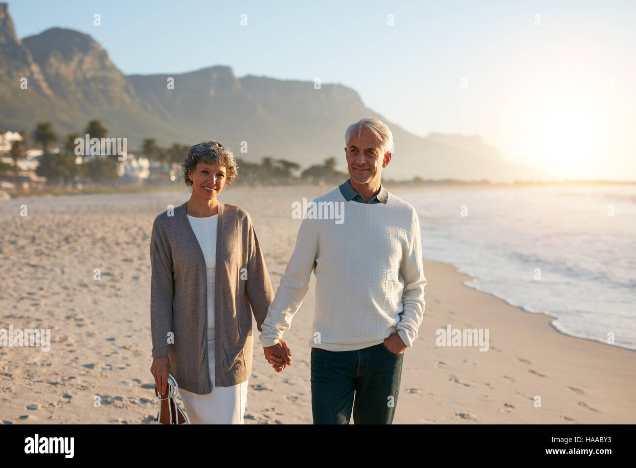 Ritratto di una felice coppia senior facendo una passeggiata sulla spiaggia insieme. Coppia matura per mano e camminare sulla riva del mare. Foto Stock